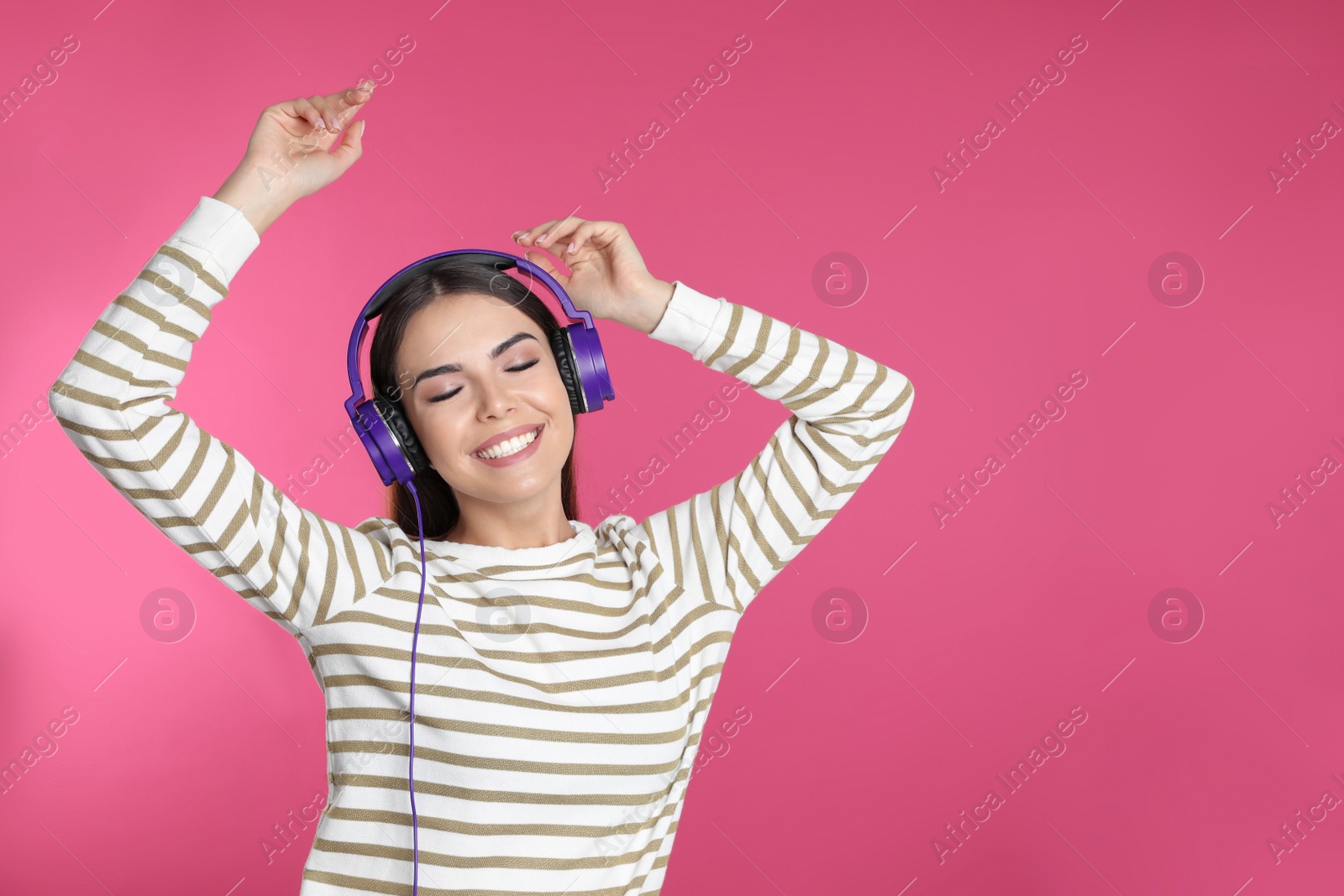 Photo of Attractive young woman enjoying music in headphones on color background. Space for text