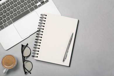 Flat lay composition with open notebook and laptop on light grey table