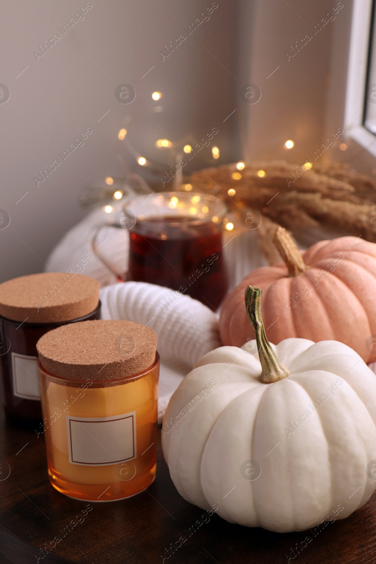 Photo of Beautiful pumpkins and candles on window sill indoors