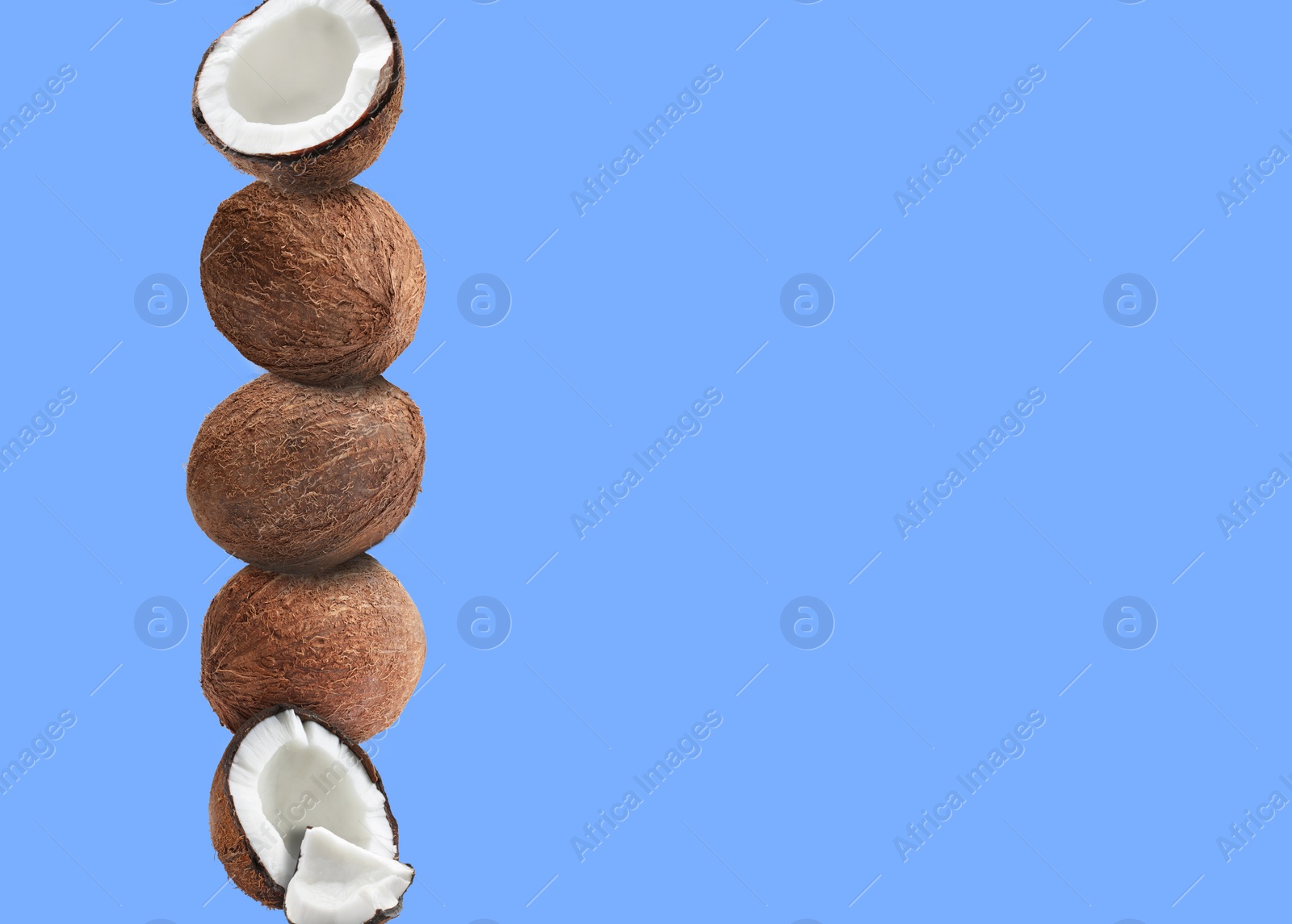 Image of Stack of fresh coconuts on pale blue background. Space for text