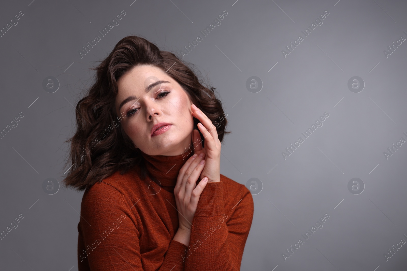 Photo of Portrait of beautiful young woman with wavy hairstyle on grey background. Space for text