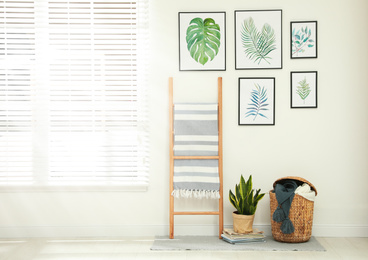 Beautiful paintings of tropical leaves on white wall in room interior