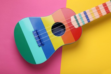 Photo of Bright ukulele on color background, top view. String musical instrument