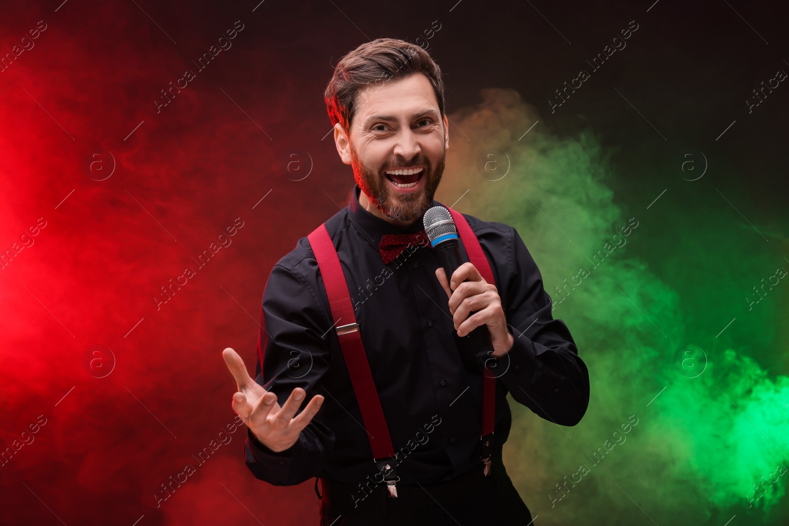Photo of Emotional man with microphone singing in color lights