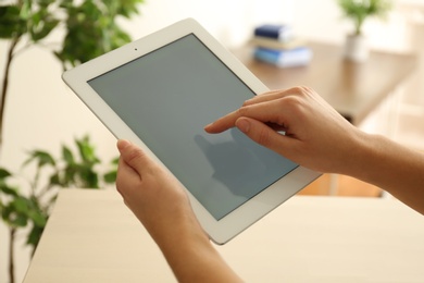 Young woman using new modern tablet indoors, closeup