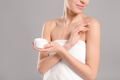 Young woman with jar of body cream on color background