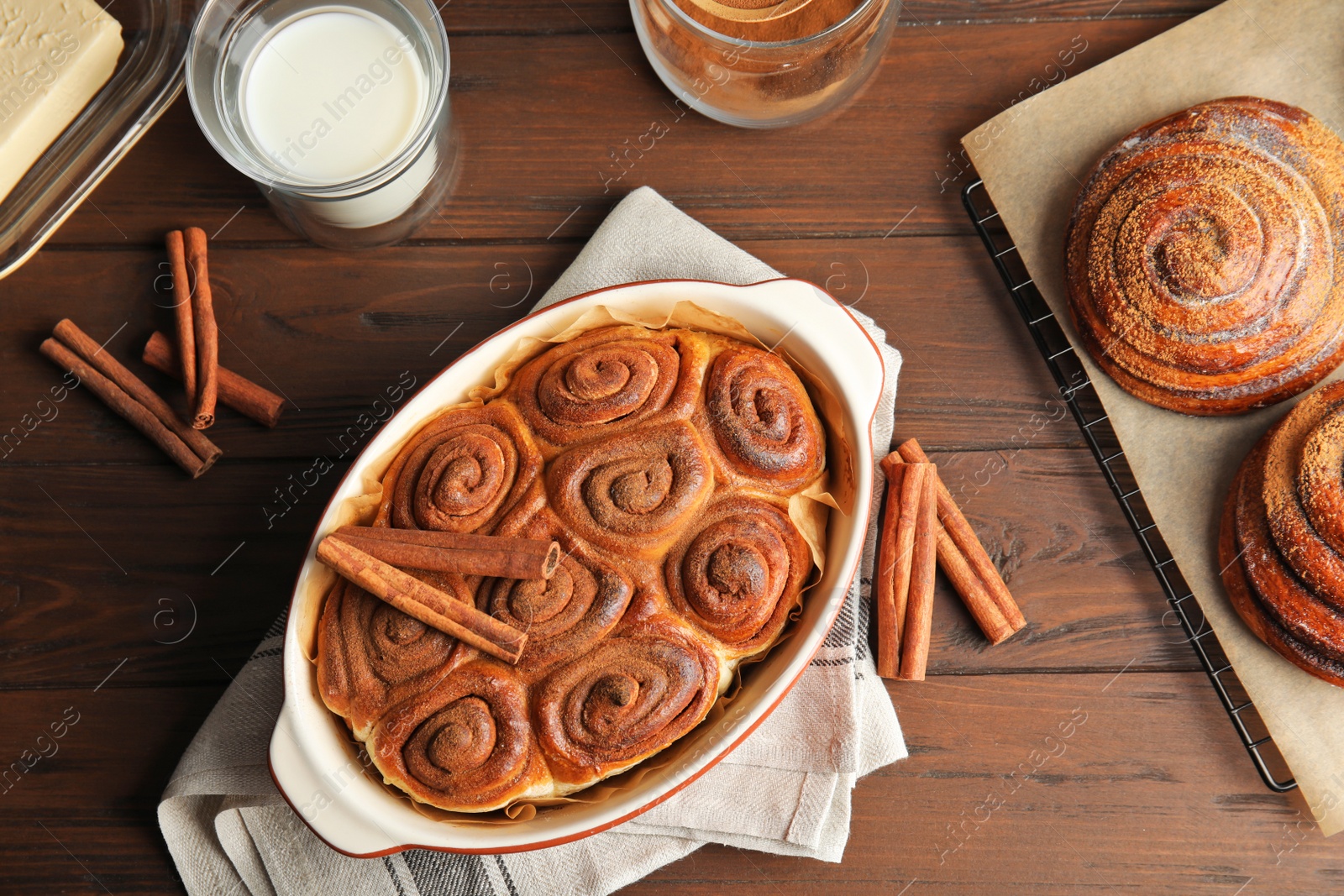 Photo of Flat lay composition with freshly baked cinnamon rolls on wooden background