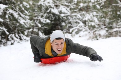 Photo of Happy man sledding outdoors on winter day. Christmas vacation