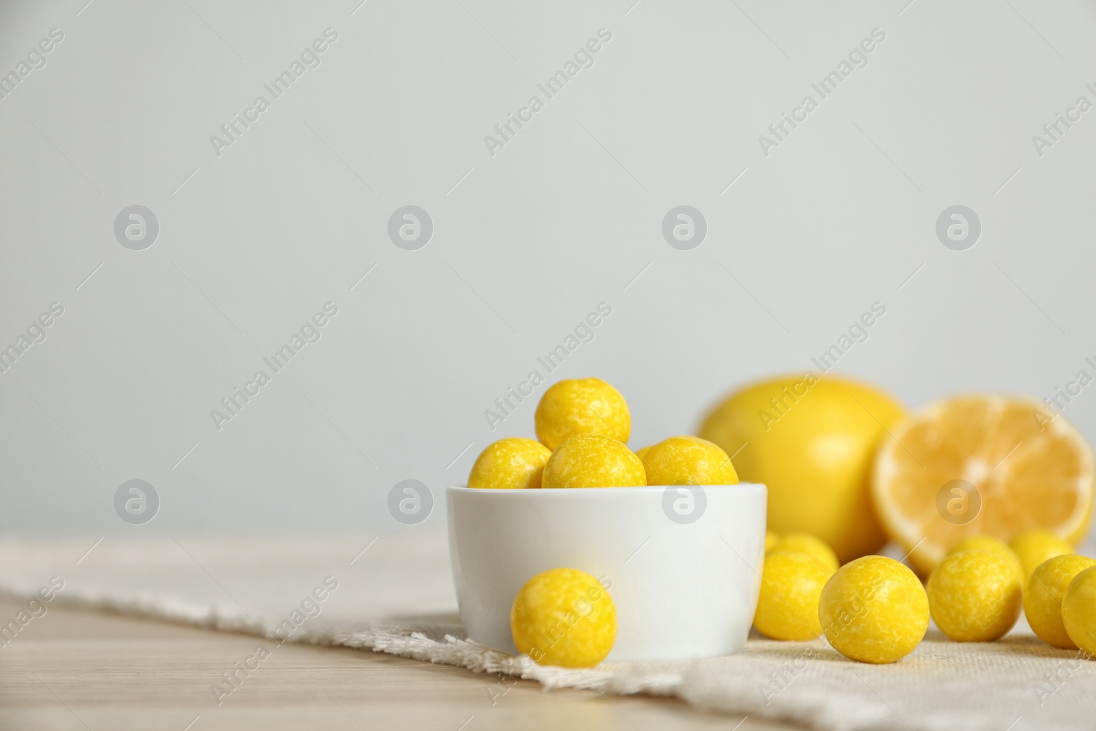 Photo of Tasty lemon drops on wooden table. Space for text