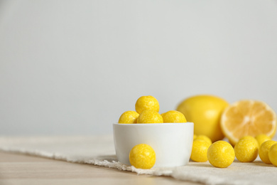 Photo of Tasty lemon drops on wooden table. Space for text