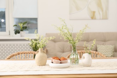 Photo of Fresh pastries and beautiful flowers on table in stylish dining room