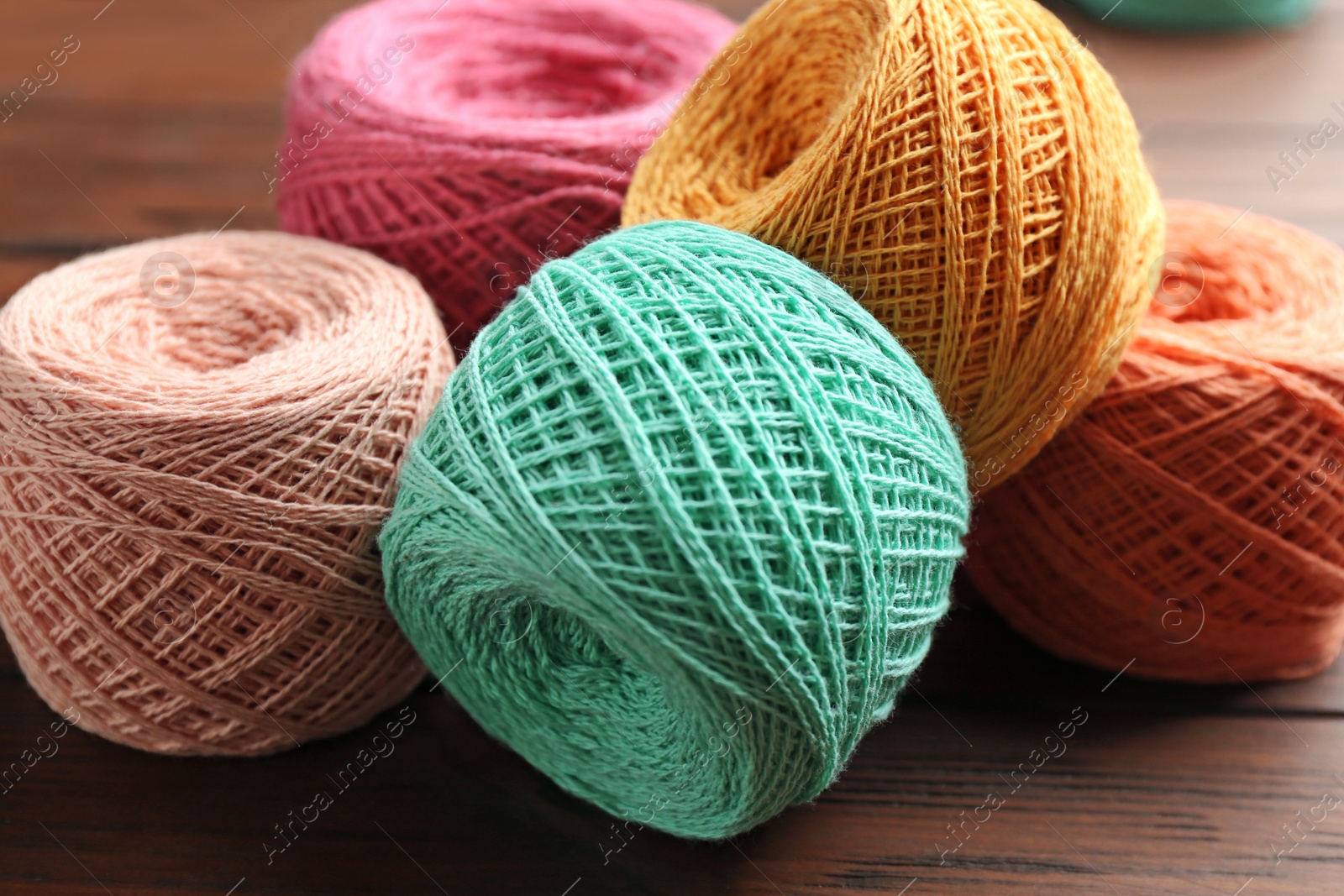 Photo of Colorful clews of threads on wooden table, closeup