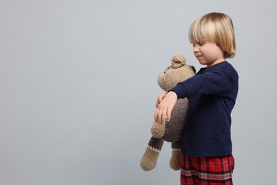 Photo of Boy in pajamas with toy bear sleepwalking on light gray background, space for text