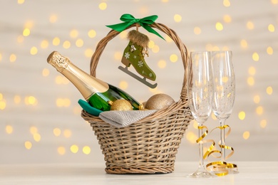 Photo of Bottle of champagne with Christmas balls in wicker basket and glasses on table