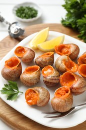 Photo of Delicious cooked snails with lemon and parsley on table, closeup
