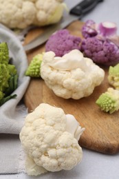 Various cauliflower cabbages on light grey table, closeup