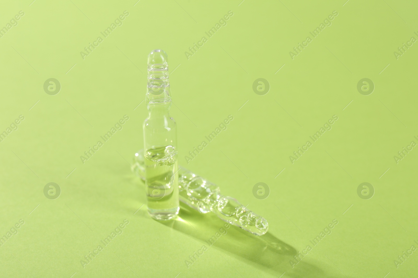 Photo of Glass ampoules with liquid on light green background