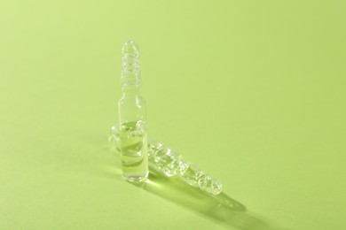 Photo of Glass ampoules with liquid on light green background