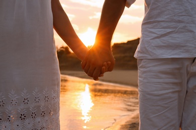 Photo of Romantic couple holding hands together on beach, closeup view