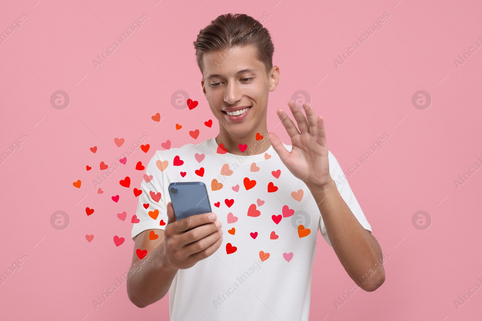 Image of Long distance love. Man video chatting with sweetheart via smartphone on pink background. Hearts flying out of device