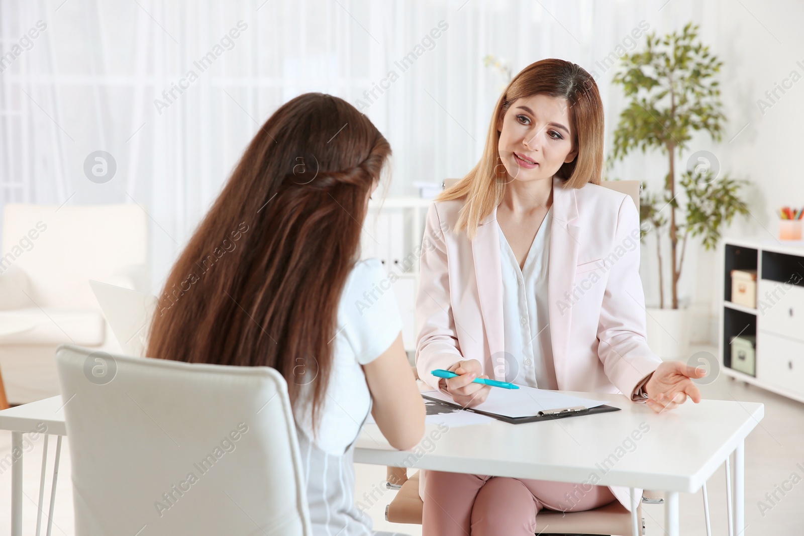 Photo of Female psychologist working with teenager girl in office