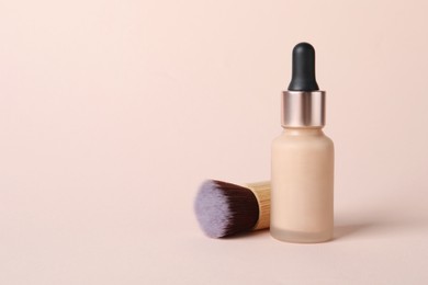 Photo of Bottle of skin foundation and brush on beige background, space for text. Makeup product