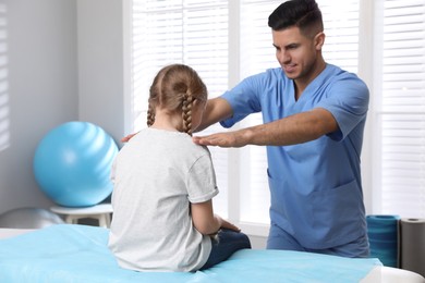 Photo of Orthopedist examining child in clinic. Scoliosis treatment