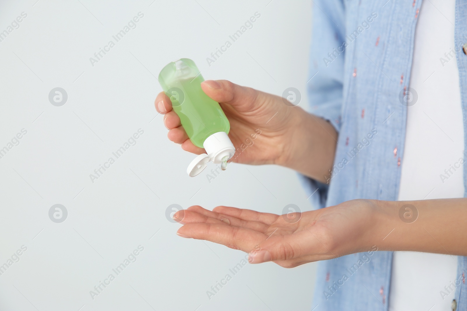 Photo of Woman applying antiseptic gel on light background, closeup