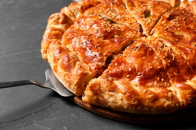 Cut delicious homemade pie and server on black table, closeup