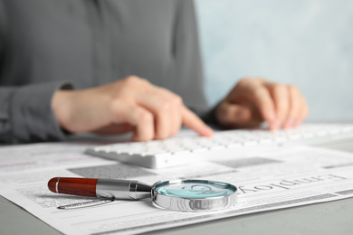 Photo of Woman at table, focus on magnifying glass. Job search concept