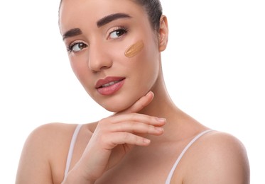 Woman with swatch of foundation on face against white background