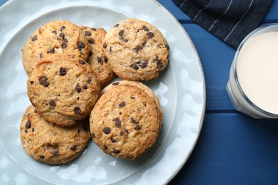 Photo of Tasty chocolate chip cookies and glass of milk on blue wooden table, flat lay