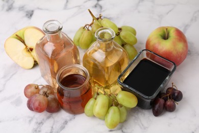 Photo of Different types of vinegar and ingredients on light marble table, closeup