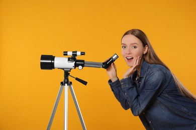 Surprised astronomer with telescope on orange background