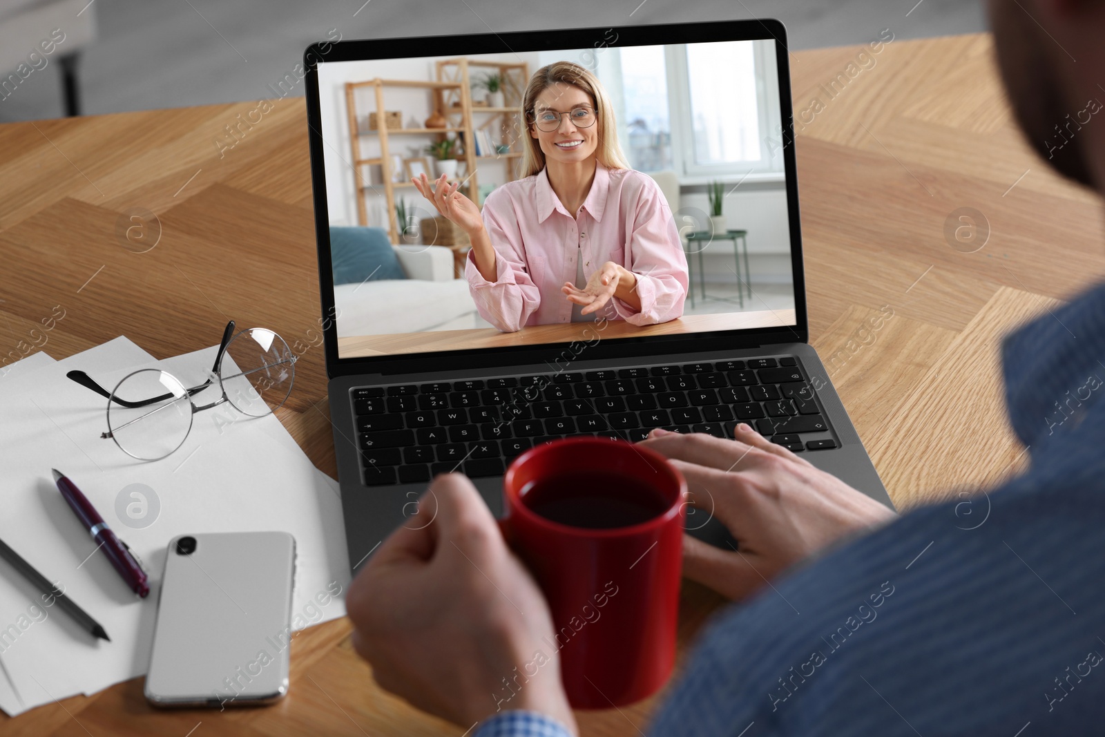 Image of Man having video chat with consultant via laptop at wooden table, closeup