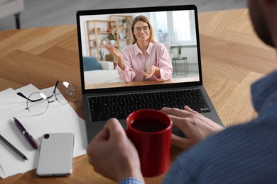 Image of Man having video chat with consultant via laptop at wooden table, closeup