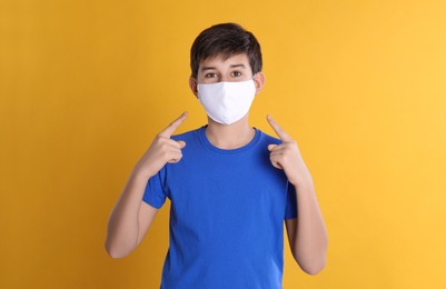 Photo of Boy wearing protective mask on yellow background. Child safety