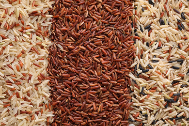 Photo of Different types of brown rice as background, top view