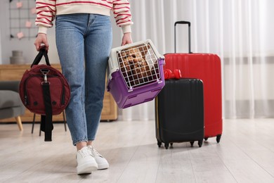 Photo of Travel with pet. Woman holding carrier with dog and bag at home, closeup. Space for text