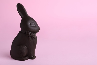 Photo of Dark chocolate bunny on pink background, space for text. Easter celebration