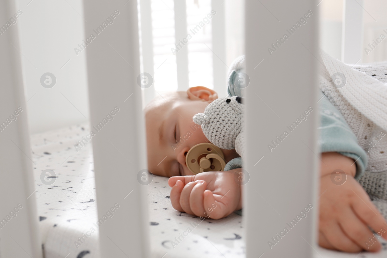 Photo of Adorable baby with toy peacefully sleeping in crib