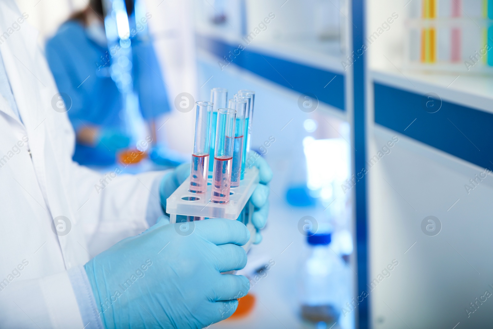 Photo of Scientist holding test tubes with liquid indoors, closeup. Laboratory analysis