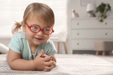 Photo of Cute little girl in glasses on floor at home. Space for text