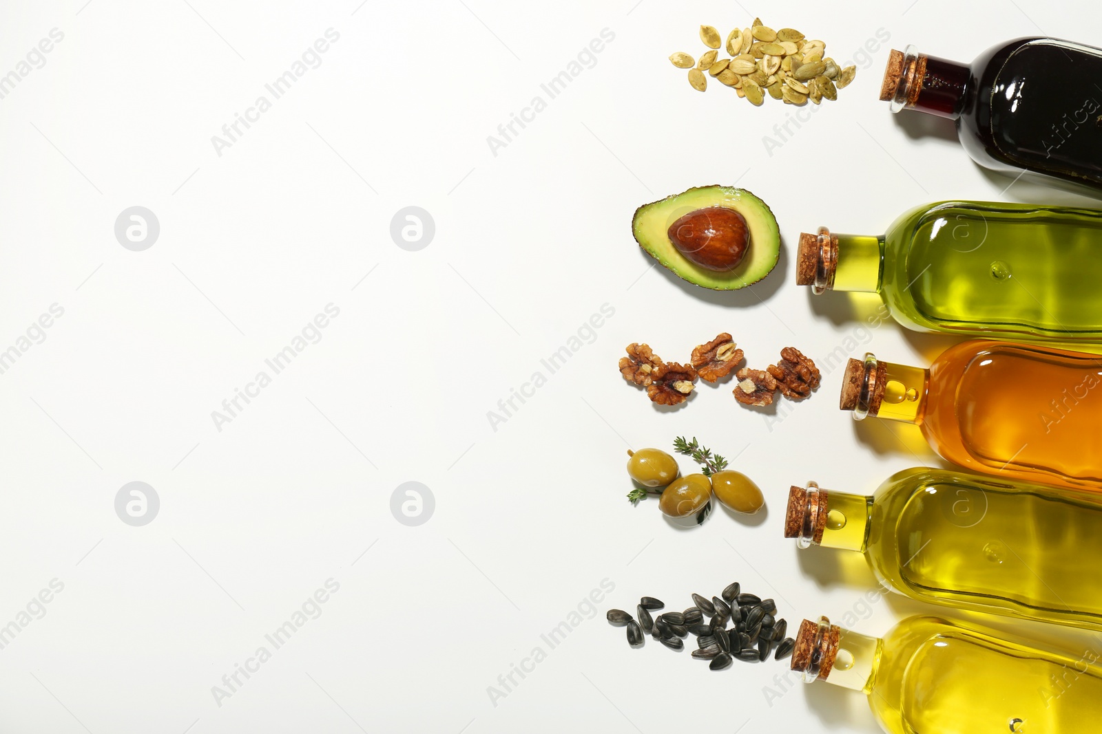 Photo of Vegetable fats. Different cooking oils in glass bottles and ingredients on white background, flat lay. Space for text