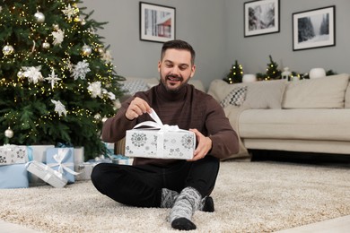 Happy man opening Christmas gift at home