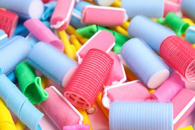 Photo of Many different hair curlers on pink background, closeup