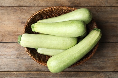 Photo of Basket of ripe zucchinis on wooden table, top view