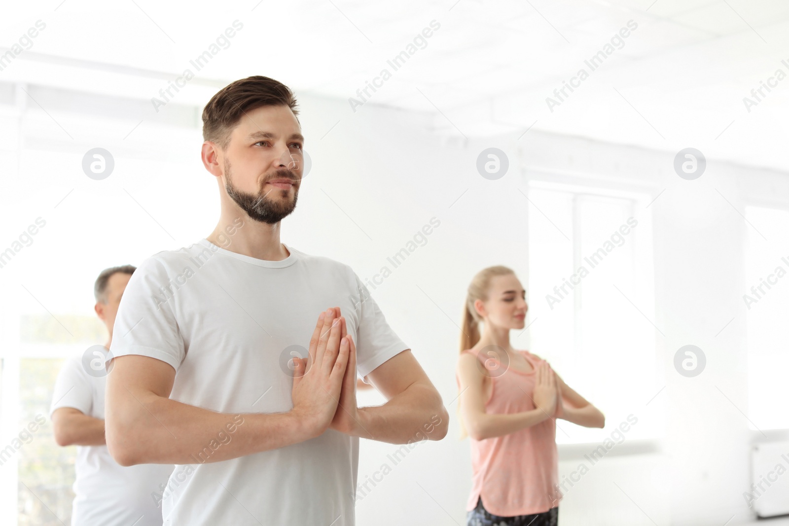 Photo of Group of people in sportswear practicing yoga indoors