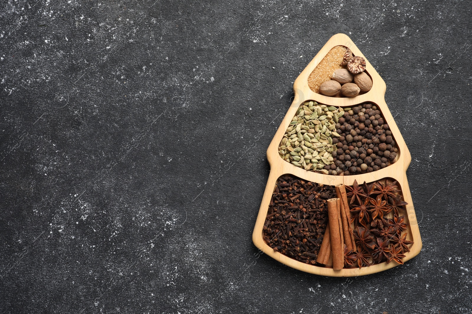 Photo of Different spices and nuts on dark gray textured table, top view. Space for text