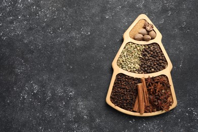 Different spices and nuts on dark gray textured table, top view. Space for text